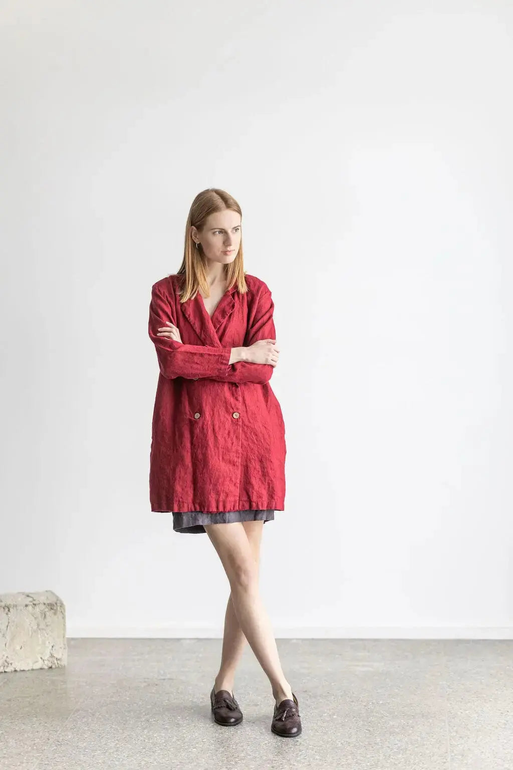 Front view of a model in a red linen jacket, crossed legs pose