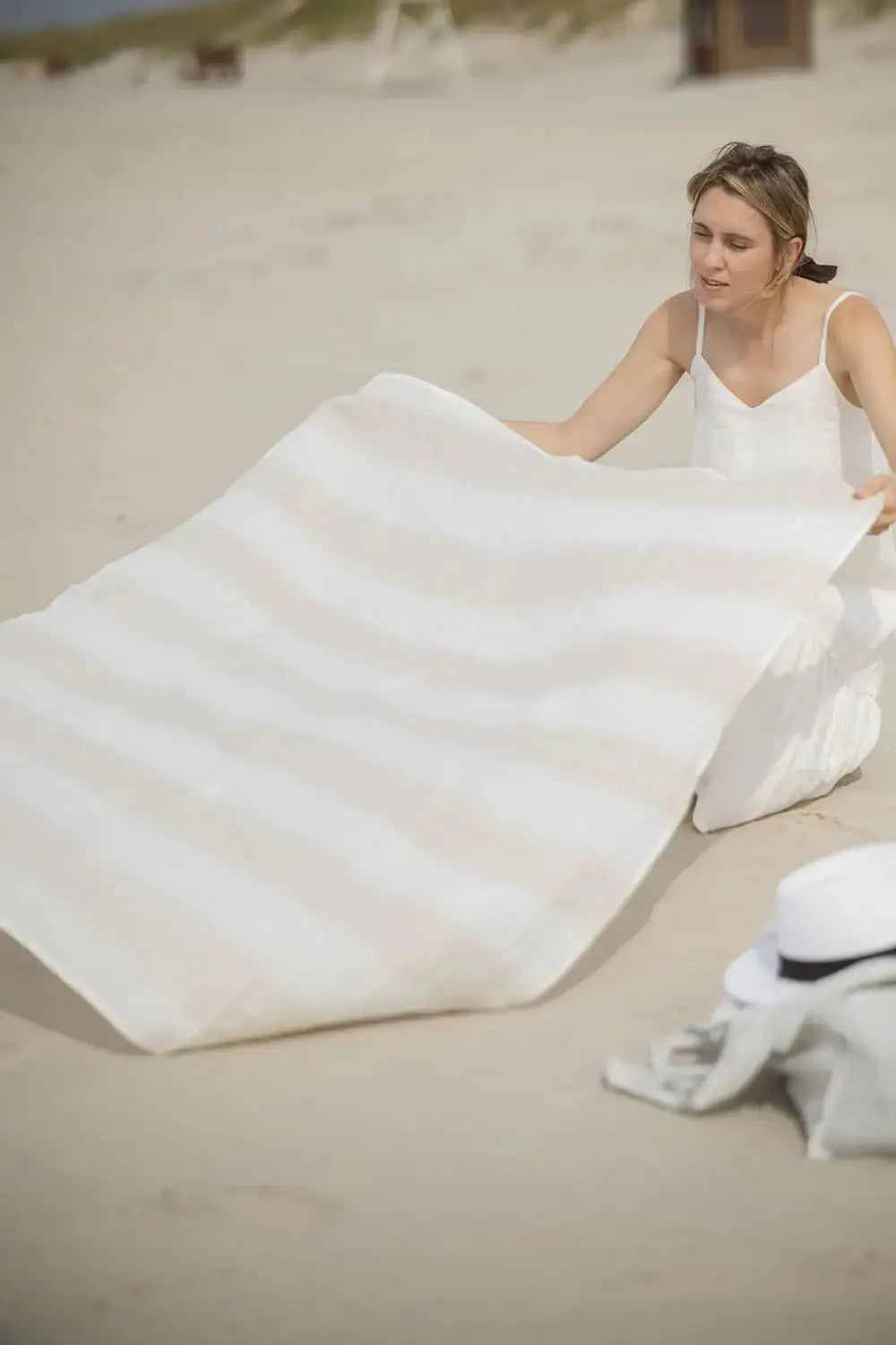 Linen Huckaback Beach Towel in white natural striped, being spread out on the beach