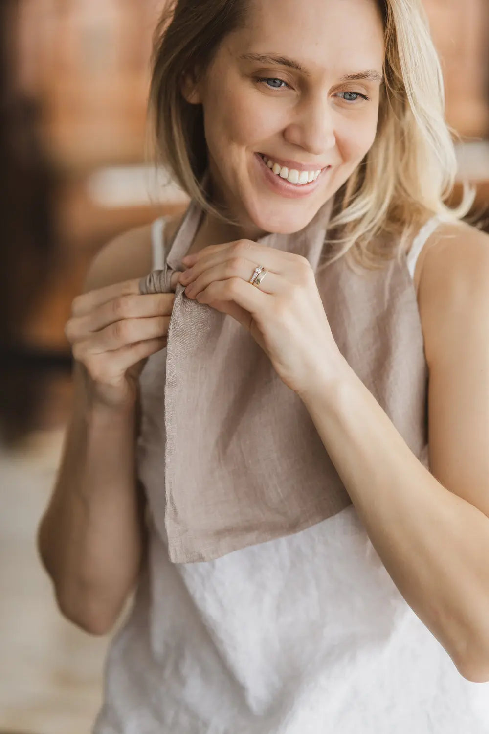 Woman wearing a light brown woven linen neck scarf with loop detail