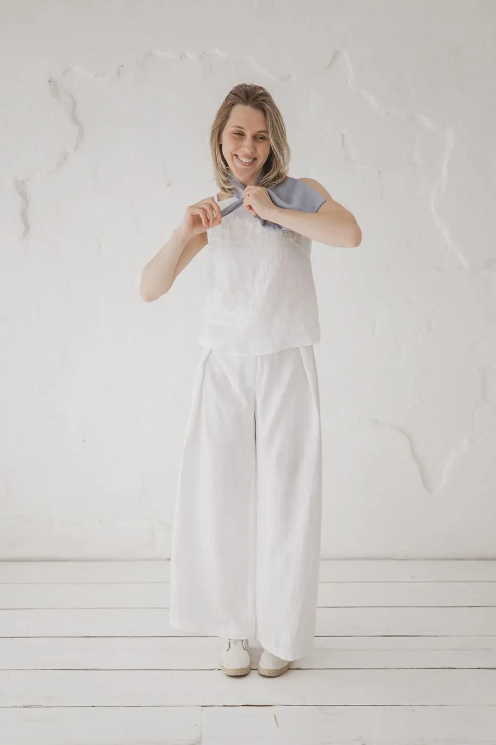 Full length view of light blue linen loop neckerchief styled with white wide-leg linen trousers