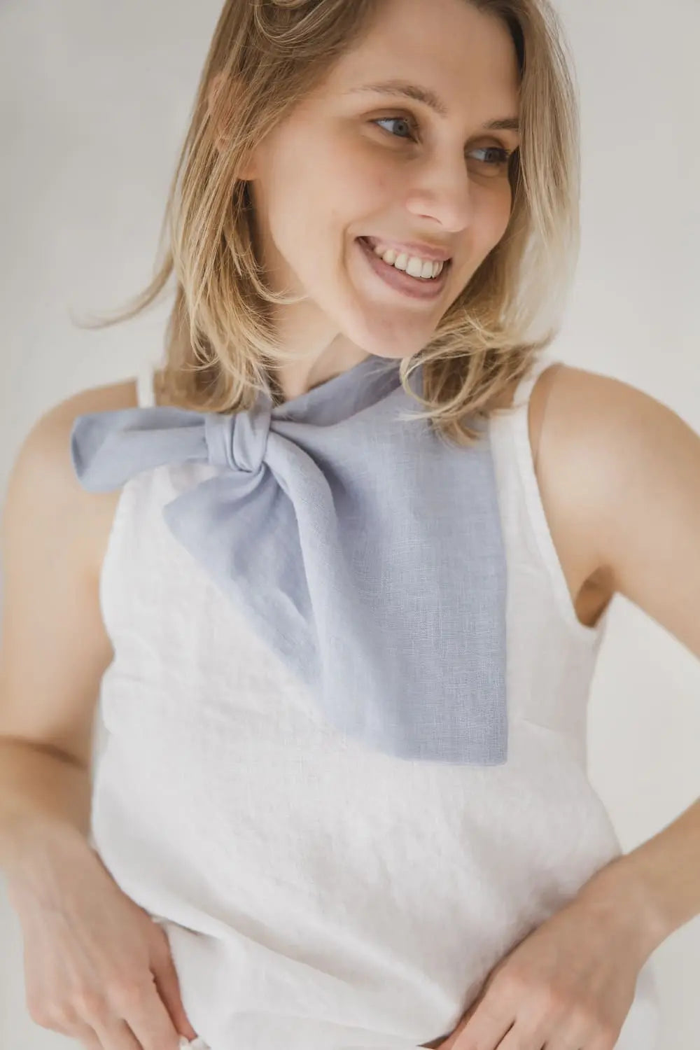 Close-up detail of light blue linen neckerchief showing pre-stitched loop and triangle drape
