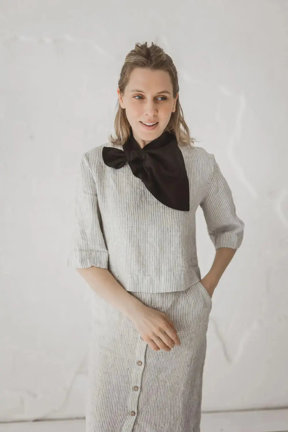 Woman wearing light black linen neckerchief with pre-stitched loop styled over striped linen outfit