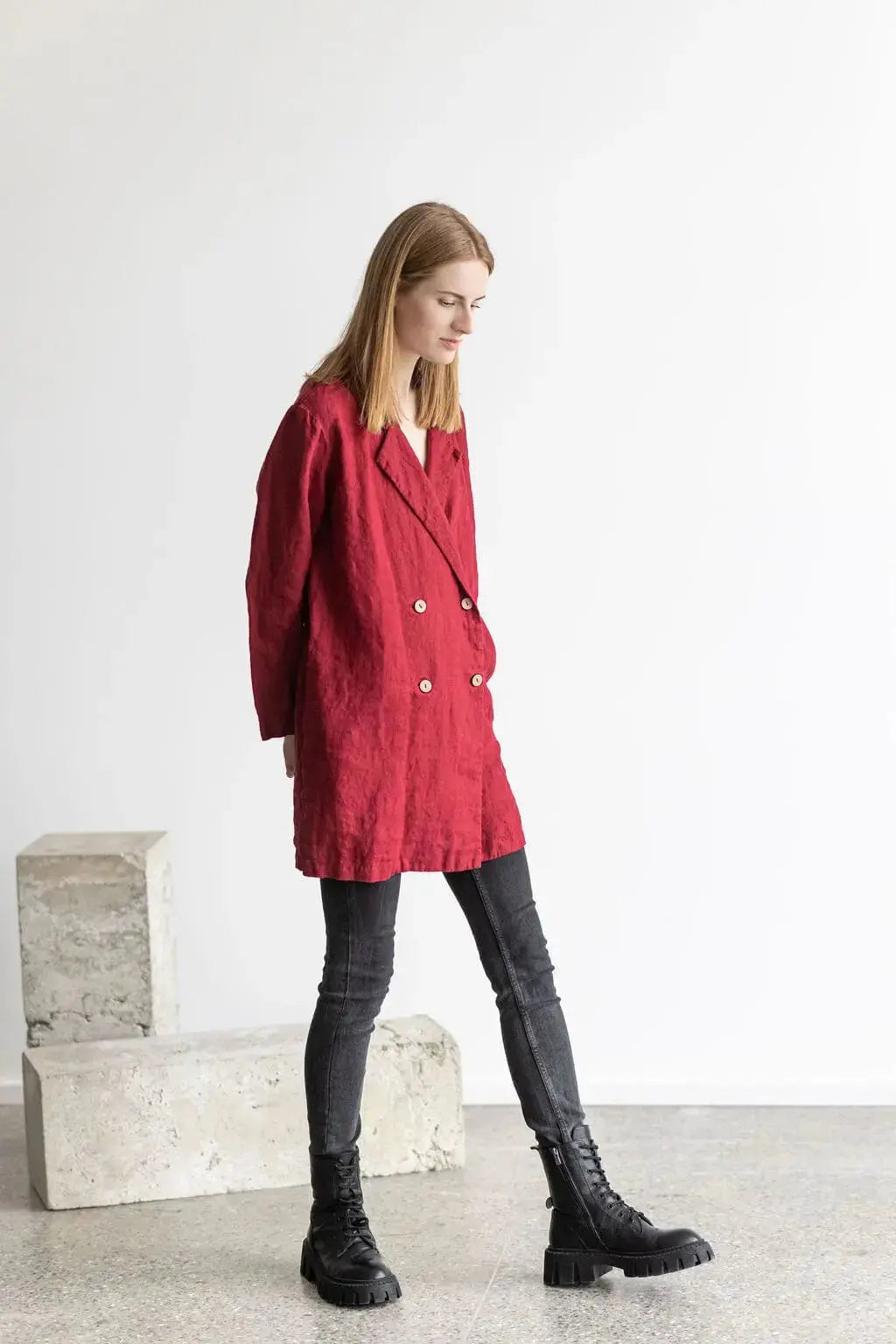 Side view of a model in a red linen jacket, dynamic walking pose